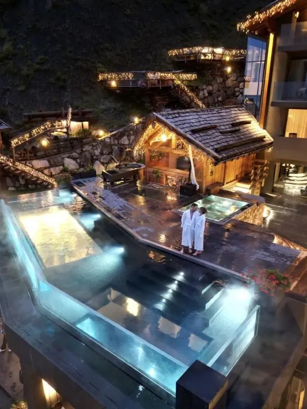 Couple in robes beside a lit infinity pool at night