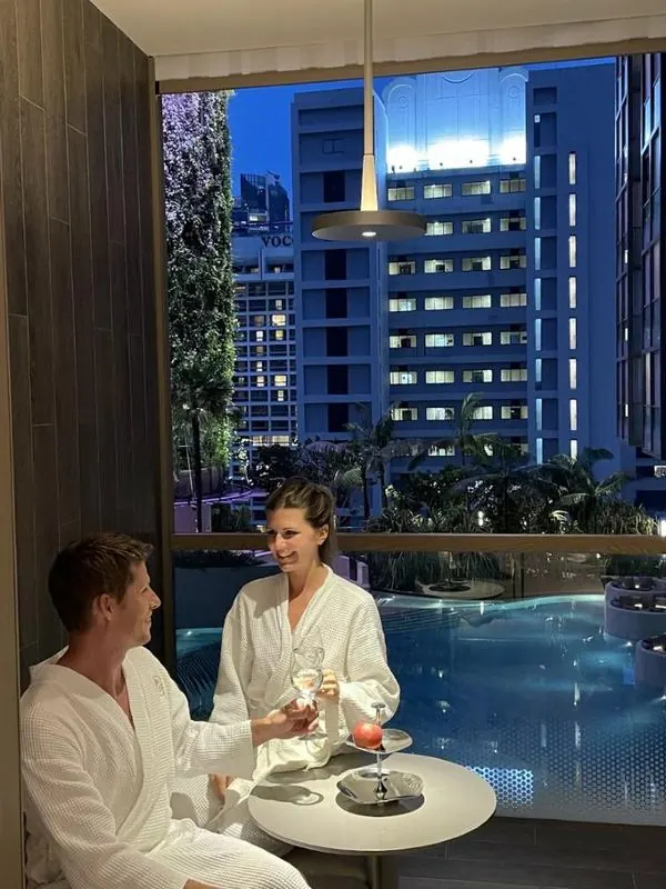 Megs and Pat in hotel robes overlooking a city pool at night